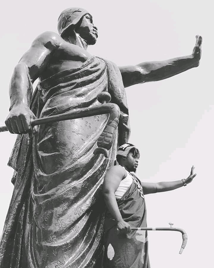 Le chanteur Crisba devant la statue du Roi Behanzin 